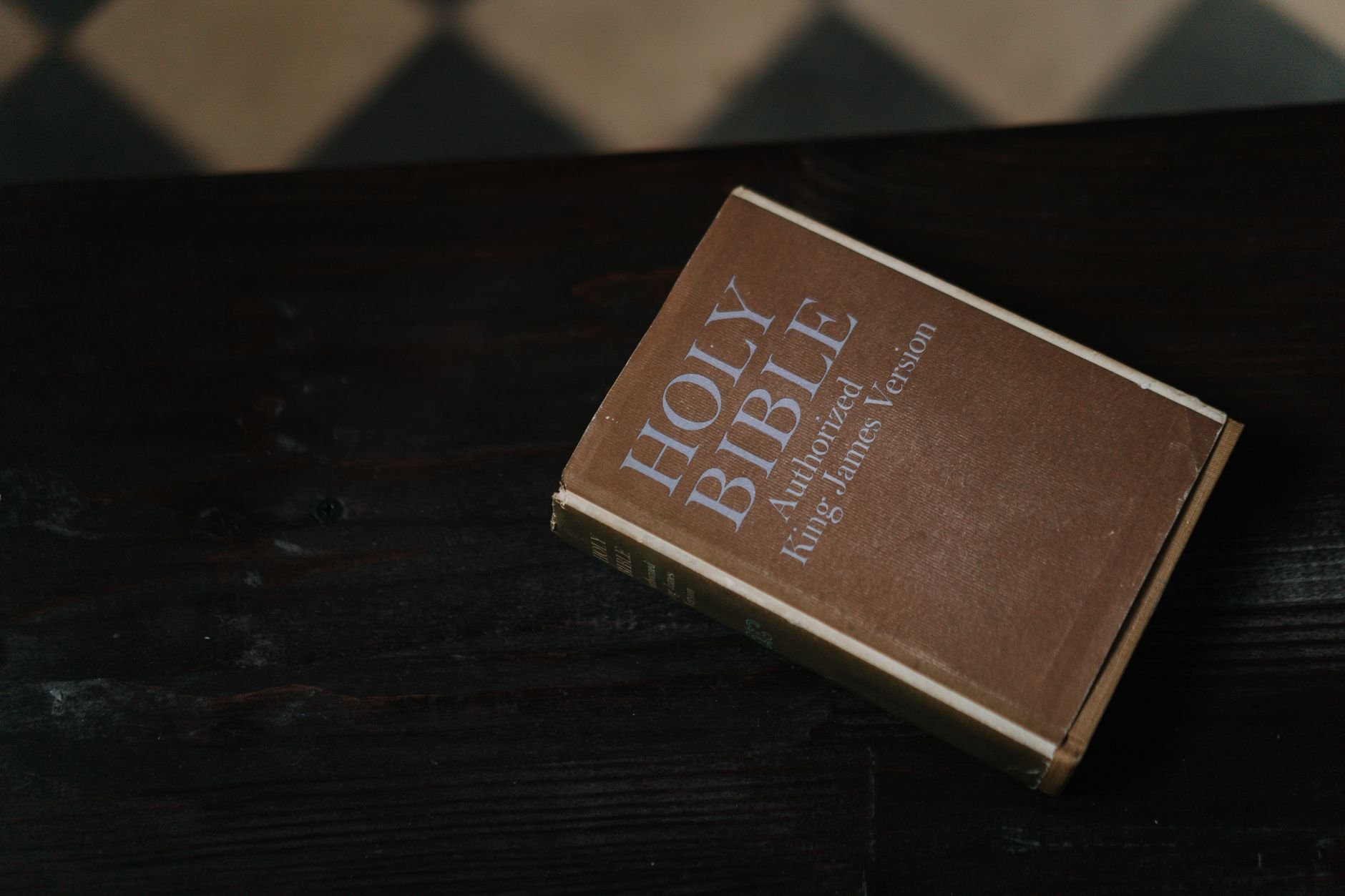 Close-up of a Holy Bible resting on a dark wooden table, symbolizing faith and spirituality.